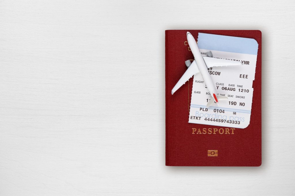 Passport, boarding pass and toy airplane on table top view